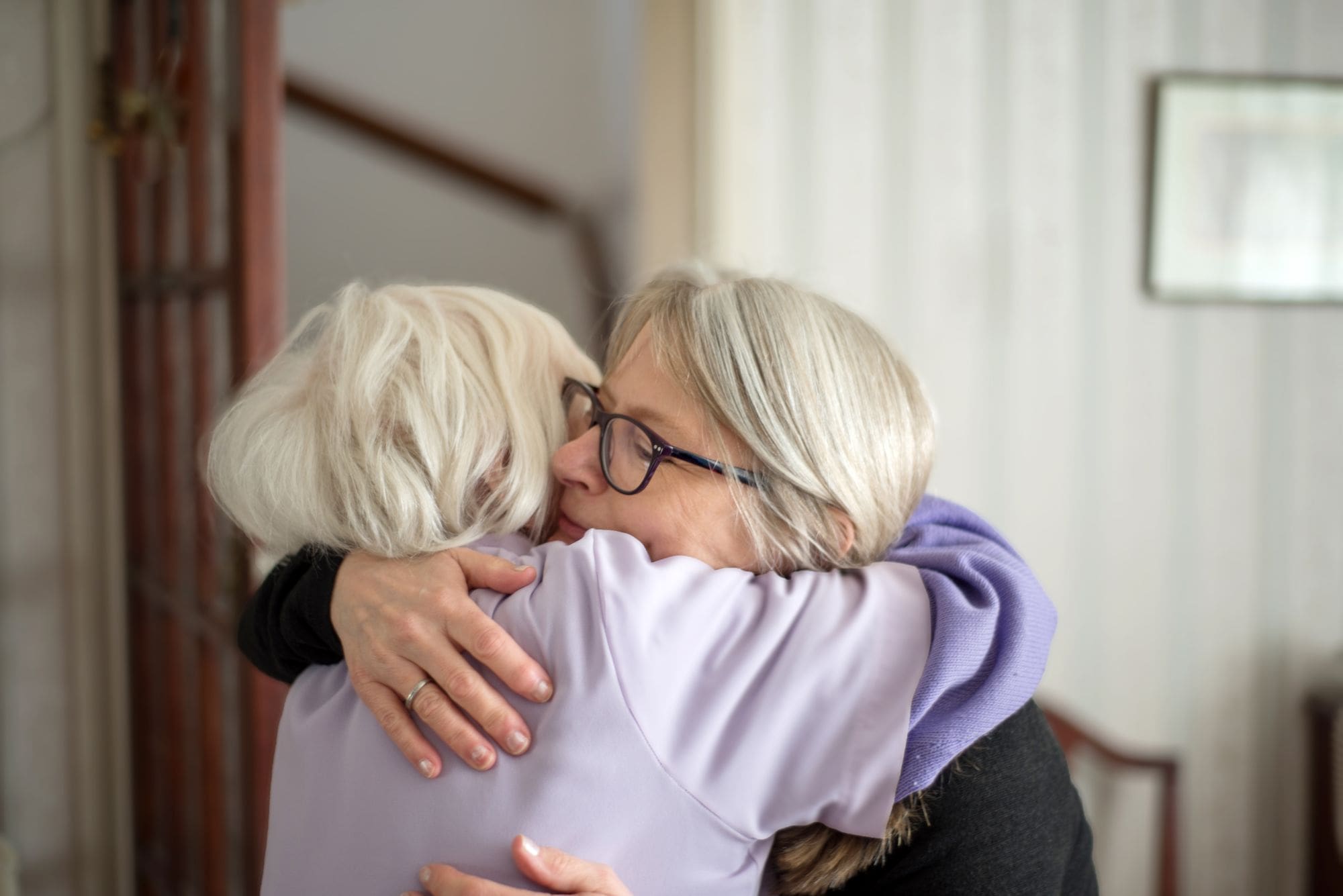 daughter hugging senior mom in living room